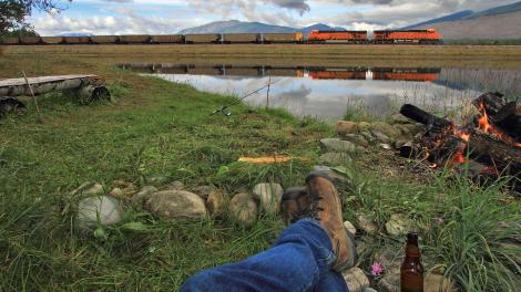 在蒙大拿州青蛙池塘的篝火前放松身心，旁边恰好有火车经过