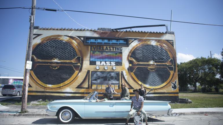 乐队在音乐主题的迈阿密壁画前合影