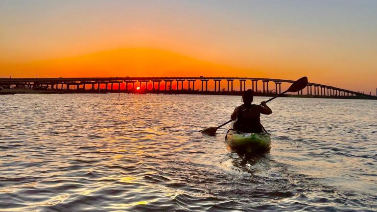 Kayaking in Lake Charles as the sun sets over the Calcasieu River Bridge