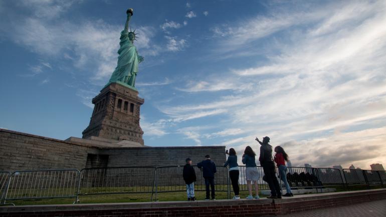 一群人在自由岛的地面上仰望自由女神像 一群人在自由岛的地面上仰望自由女神像