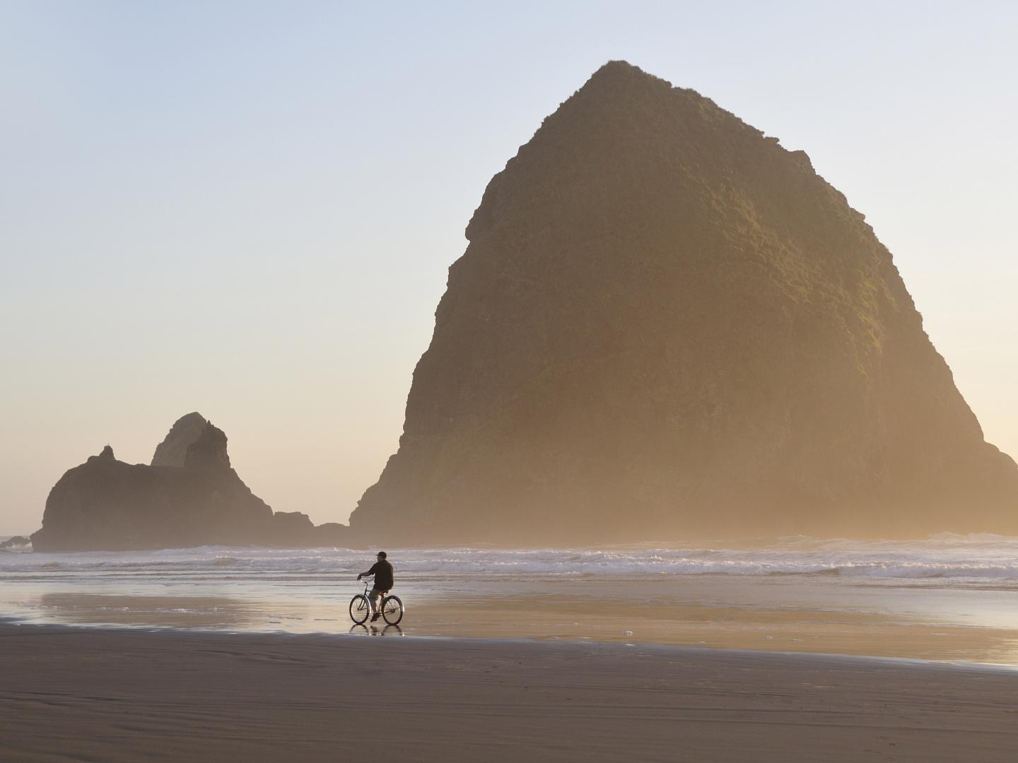 在坎农比奇草垛岩前骑自行车