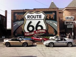 Antique Pontiac Fieros parked in front of the Route 66 mural at the Route 66 Hall of Fame & Museum