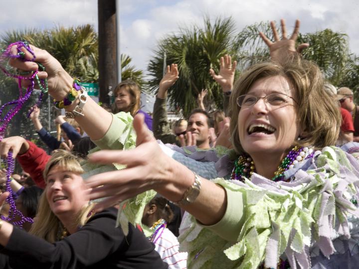 Fiesteros atrapando cuentas en el desfile de Mardi Gras en Lafayette