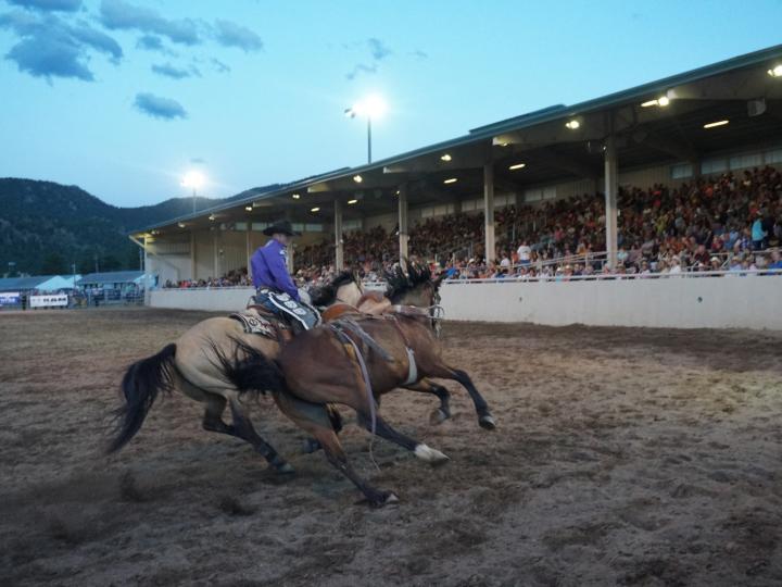 Presentación de vaquero cabalgando a ritmo rápido en el Rooftop Rodeo de una semana, en Estes Park