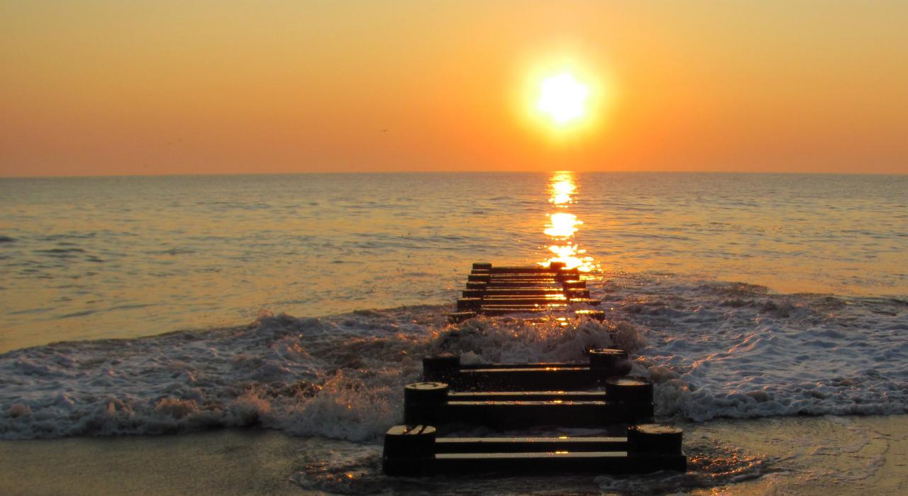 夕阳下海浪拍打着废弃的码头