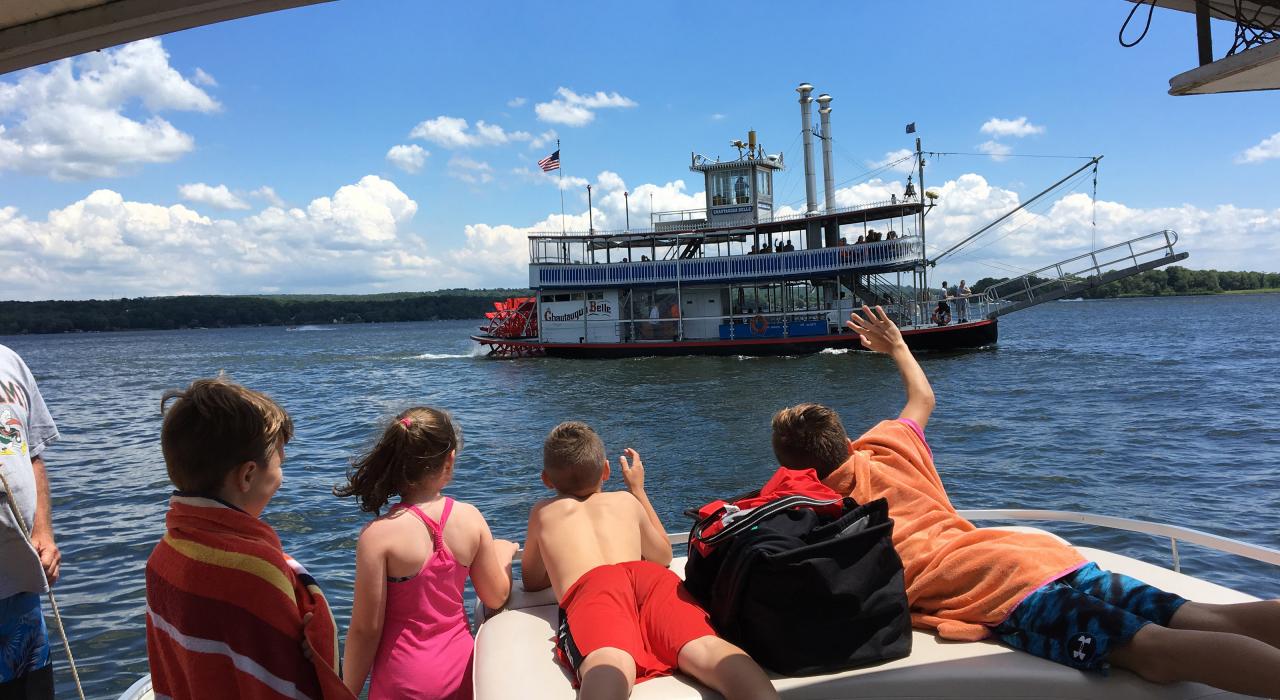 向登上肖托夸湖上的 Chautauqua Belle 明轮船巡游的乘客挥手