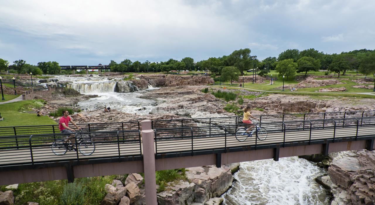 在南达科他州苏福尔斯的瀑布公园内骑车穿过横亘在瀑布上方的桥梁