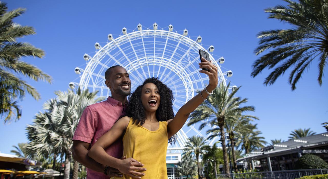 Pareja posando frente a The Wheel en ICON Park en Orlando, Florida