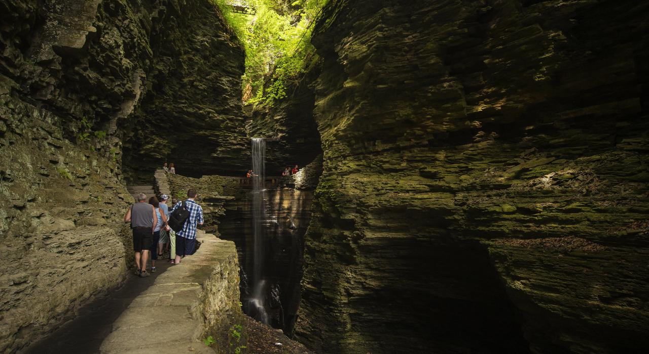 到访沃特金斯峡谷州立公园的游客惊叹于 Cavern Cascade 瀑布之美