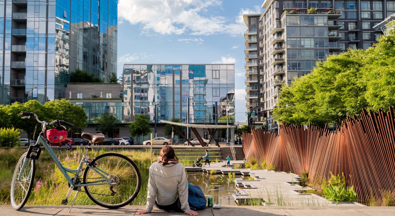 在生机勃勃的珍珠区，一位骑行者正在 Tanner Springs Park 公园惬意休息