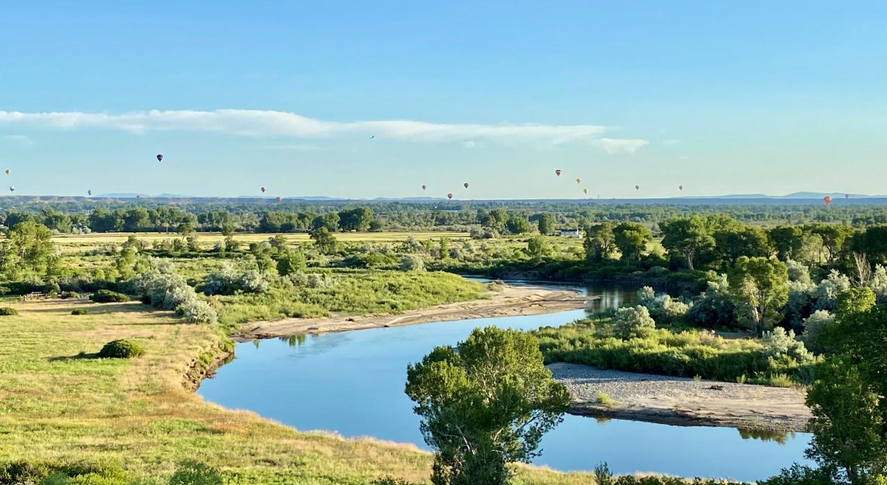 在一年一度的里弗顿会合点热气球大会上，热气球在风河上空徐徐升起